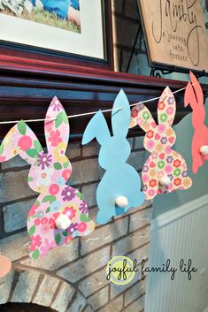 some paper bunnies are hanging on a clothes line in front of a brick fireplace