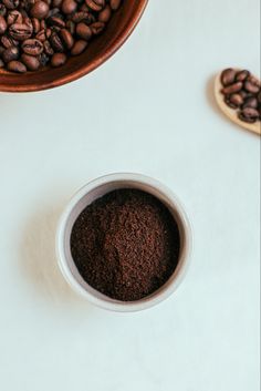 two bowls filled with coffee beans next to each other on a white counter top,