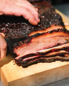 someone cutting up some meat on top of a wooden board