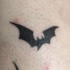 a close up of a person's chest with a bat tattoo on the side