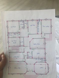 a person holding up a blueprint drawing of a floor plan in front of them