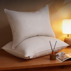 two pillows on a table next to a lamp