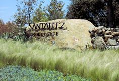 there is a sign that says sandaluz north gate in front of some tall grass