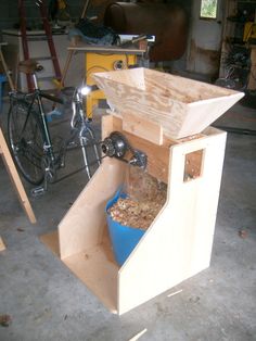 a blue bucket filled with food inside of a wooden box next to a bike in a garage