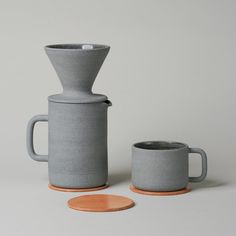 a gray coffee pot and cup sitting next to each other