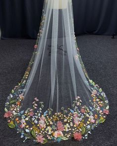 a wedding veil with flowers and leaves is on display in front of a black backdrop