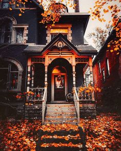 a house with fall leaves on the ground and stairs leading up to it's front door