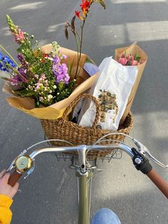 a person riding a bike with flowers in the basket on the handlebars,