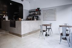 an empty restaurant with tables and chairs in front of the counter, along with shelves on the wall