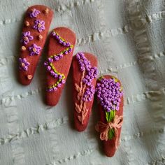 three red shoes with purple flowers on them sitting on a white cloth covered tablecloth