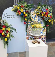 two cakes decorated with fresh flowers and greenery on display at a kitchen tea event