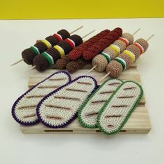 several skewers of different colors and sizes on a wooden board with crocheted strips