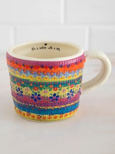 a colorful coffee cup sitting on top of a table