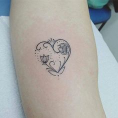 a small heart tattoo on the left arm with flowers and leaves in it's center