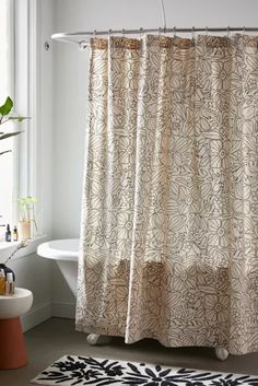 a bathroom with a bathtub, rug and shower curtain that has an abstract design on it