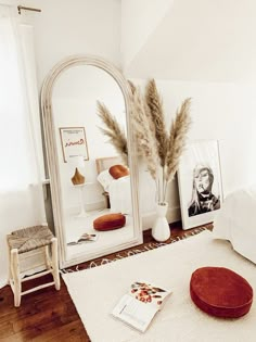 a bedroom with a mirror, stool and pictures on the wall next to a bed