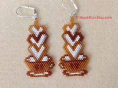 two brown and white beaded earrings with hearts on them sitting on top of a table