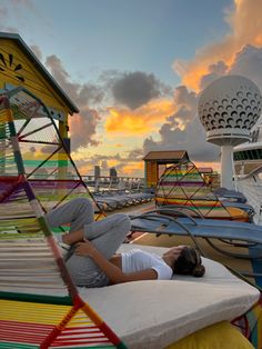 a woman laying on top of a bed next to a colorful structure at the beach