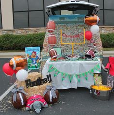 a table with football decorations and balloons in front of a van