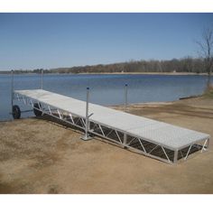 a boat dock sitting on top of a sandy beach next to a lake in the daytime