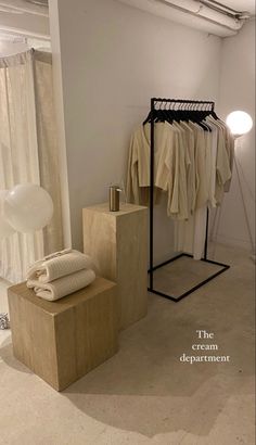 an empty room with clothes hanging on racks and a lamp next to the clothing rack