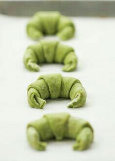 four pieces of green cake sitting on top of a white counter next to a knife