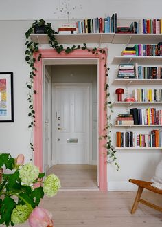 a room with bookshelves filled with lots of books next to a white door