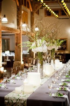 the table is set with candles and flowers in vases on top of each other