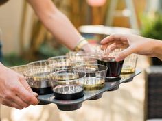 several people are serving themselves drinks on a tray with wine glasses in each others'hands