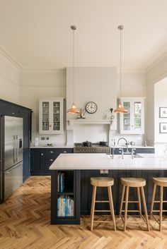 a kitchen with two stools and an island in the middle, surrounded by wooden flooring