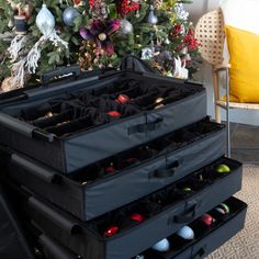 the christmas tree is decorated with ornaments in black plastic boxes and hanging from it's branches