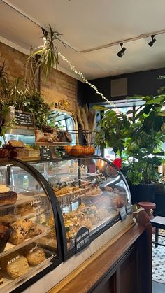 a bakery filled with lots of pastries and plants on the wall behind the counter