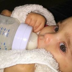 a baby drinking from a bottle while wrapped in a blanket