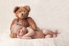 a baby sleeping next to a teddy bear on top of it's back and head