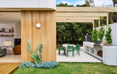 an outdoor kitchen and dining area with cactus plants in the foreground, next to a covered patio