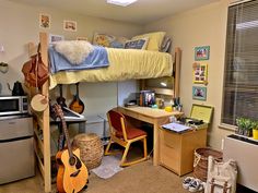 a bedroom with a bunk bed, desk and guitar