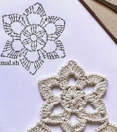 the crocheted snowflake is laying on top of paper