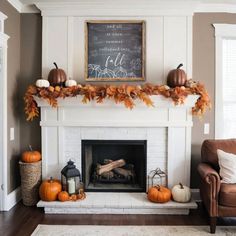 a fireplace decorated for fall with pumpkins, leaves and a chalkboard on the mantle