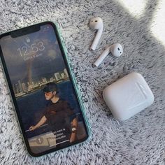 an iphone, ear buds and headphones on a carpet