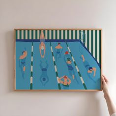 a person holding up a painting with swimmers on it