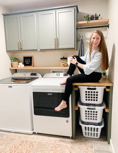 a woman sitting on top of a counter next to a washer and dryer