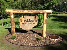 a wooden sign sitting in the middle of a lush green field