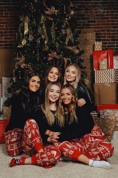 group of women sitting in front of christmas tree