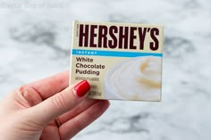 a hand holding up a hershey's chocolate pudding bar in front of a marble background