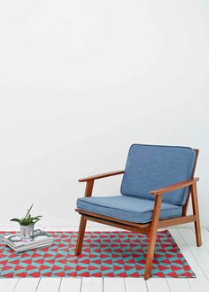 a blue chair sitting on top of a rug next to a potted green plant