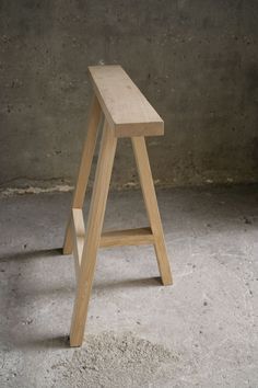 a wooden stool sitting in the middle of a room with concrete flooring and walls