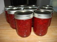 there are many jars that have red liquid in them and silver lids on each one