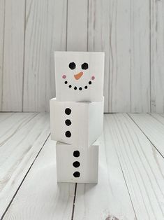 a snowman made out of cardboard sitting on top of a wooden floor next to a white wall