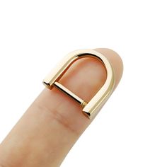 a person's finger with a gold ring on top of their thumb and the letter d in the middle