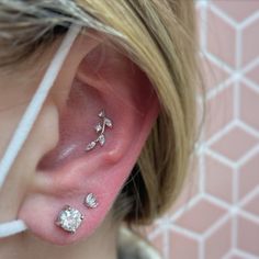 a close up of a person's ear with three different piercings on it